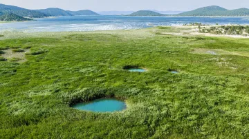 V pozadí snímku je vidět zbytek jezera, v popředí jeho polovyschlé dno, odkud už voda většinou ustoupila