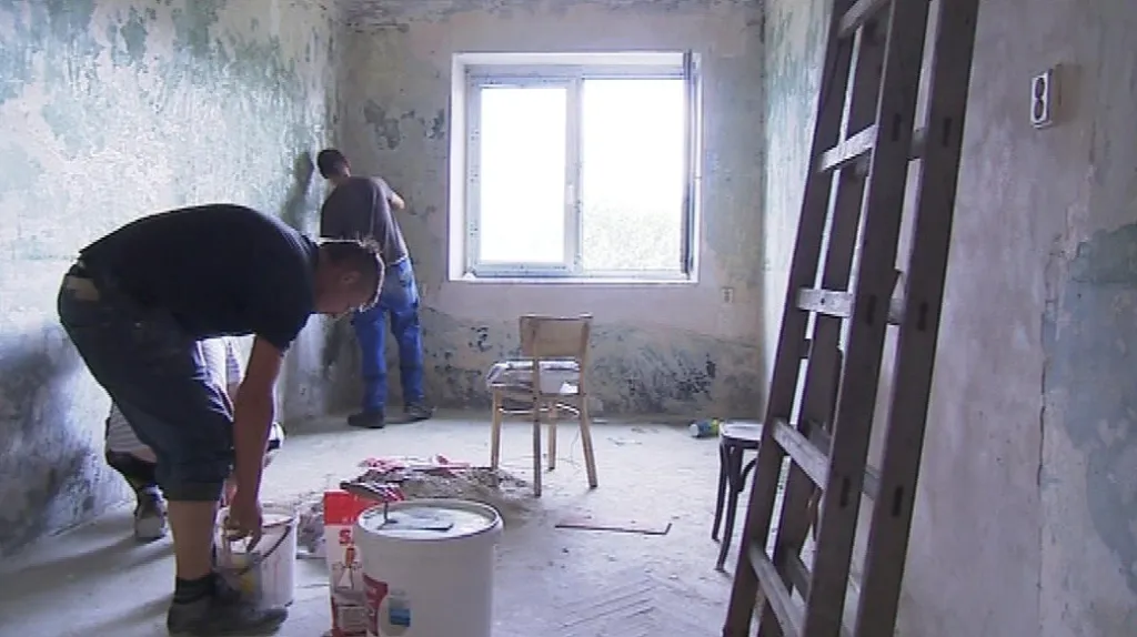 Lidé bez domova pracují na opravě domu