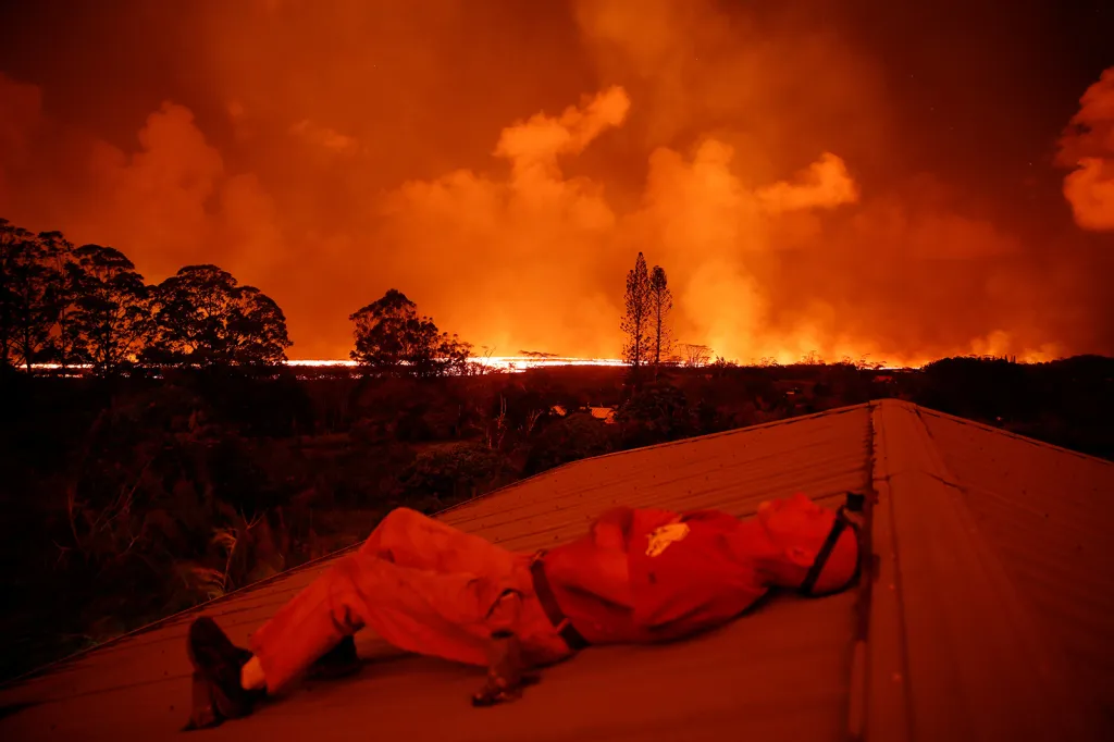 Mark Clawson sleduje nebe zbarvené chrlící lávou při odpočinku na střeše jednoho z domů na okraji města Pahoa během divokých a smrtících erupcí vulkánu Kilauea na Havaji.