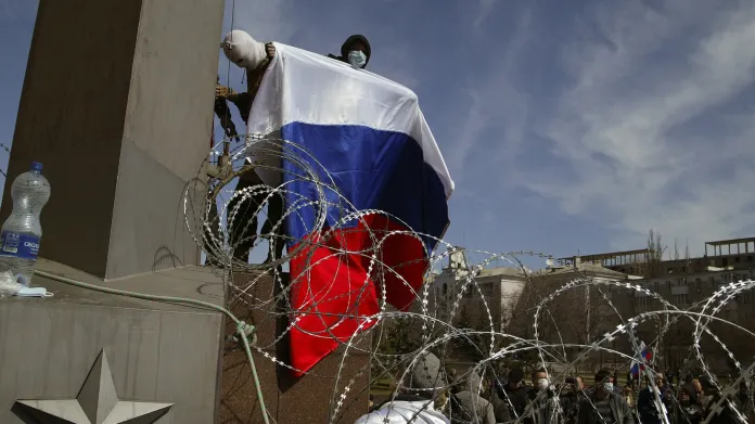 Maskovaný muž držící ruskou vlajku v Doněcku