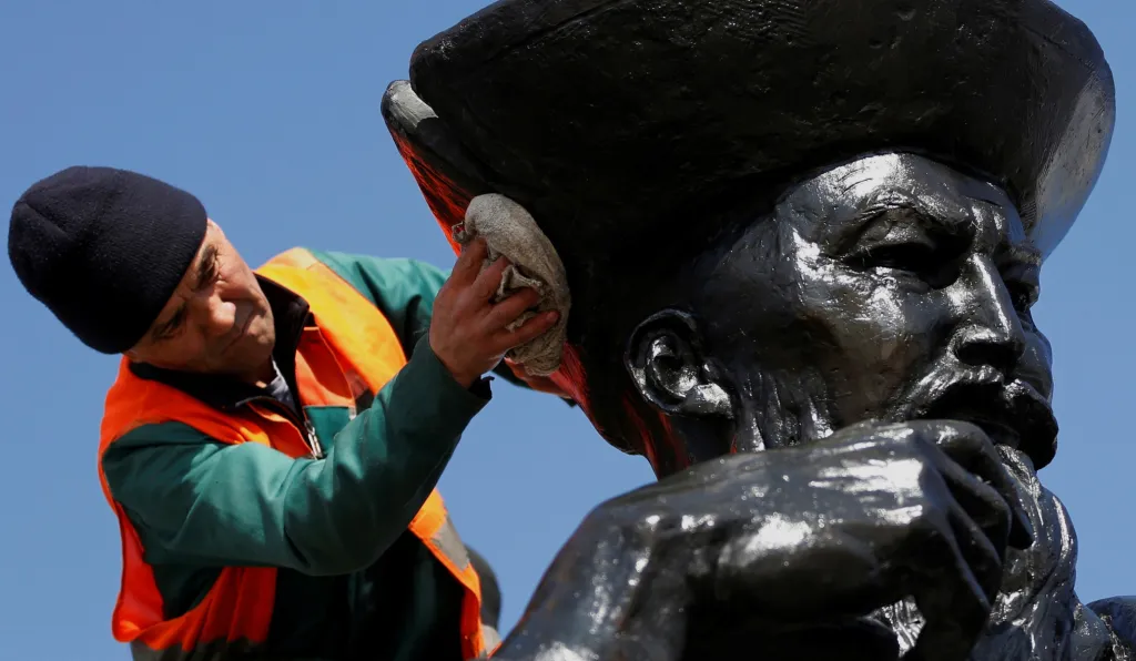 Pracovník údržby čistí hlavu sochy, která je součástí Památníku nezávislosti v kazašském Almaty