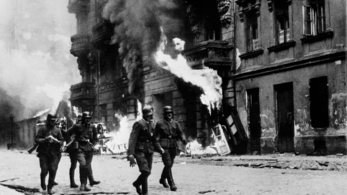 Němečtí vojáci procházejí hořícím varšavským ghettem