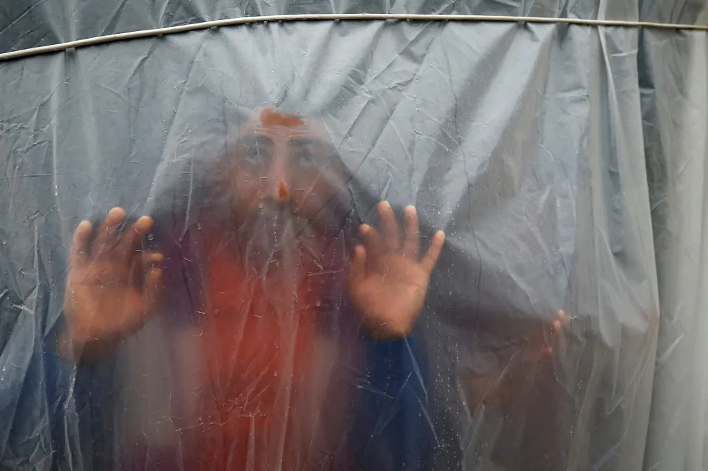 Palestinec se dívá skrz plastovou fólii zakrývající jeho částečně zničený dům ve městě Bajt Lahíja na severu Pásma Gazy