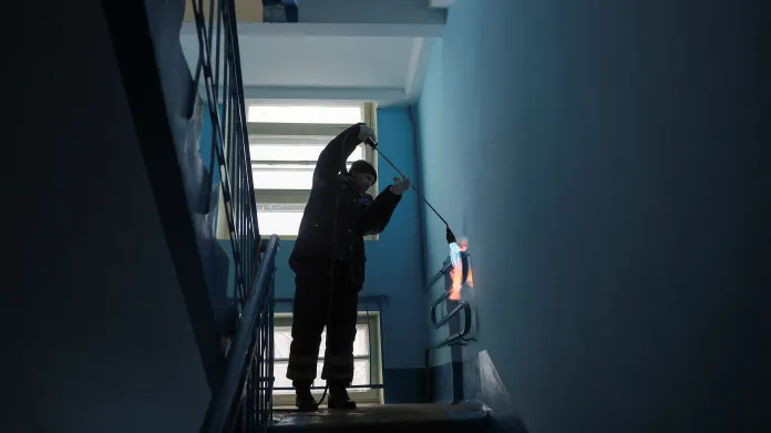 Specialista ohřívá potrubí v několikapatrovém bytovém domě v Podolsku