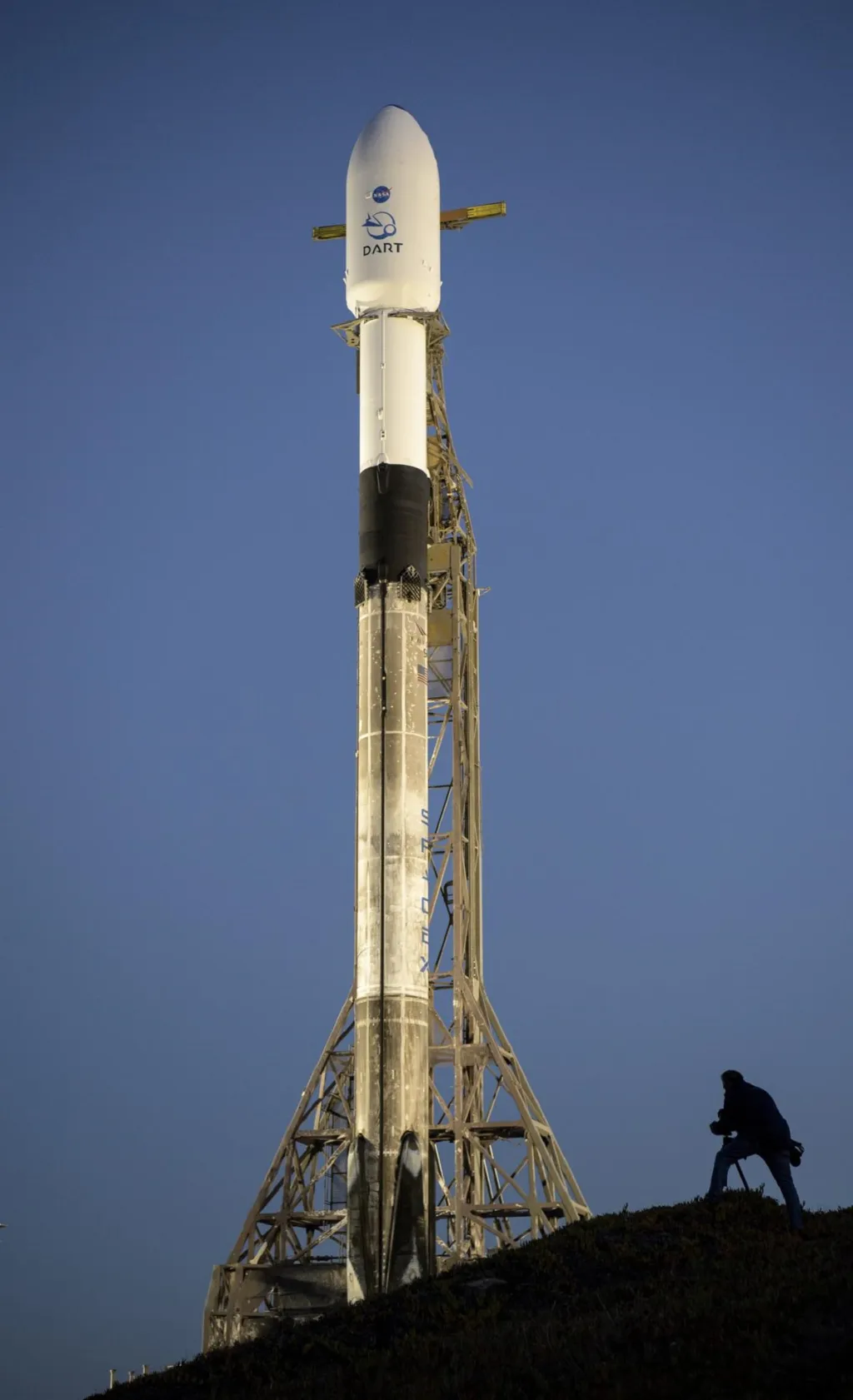 Raketa Falcon 9 společnosti SpaceX s kosmickou lodí DART (Double Asteroid Redirection Test) na palubě je vidět při východu slunce v úterý 23. listopadu 2021 na kosmodromu 4E na Vandenbergově základně v Kalifornii. DART je první plnohodnotný test planetární obrany na světě, který demonstruje jednu z metod technologie odklonění asteroidů