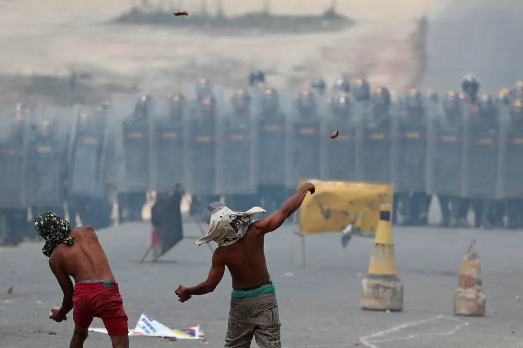Venezuelští demonstranti házejí kameny na policejní složky u hranice s Brazílií při protestech proti blokování potravinové pomoci