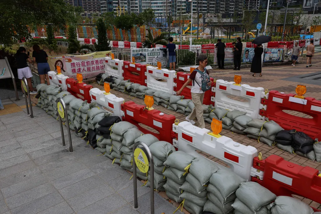 Obyvatelé Hongkongu procházejí kolem pytlů s pískem