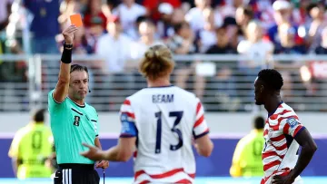 Rozhodčí Raphael Claus ukazuje útočníkovi americké reprezentace Folarinu Balogunovi (vpravo) červenou kartu