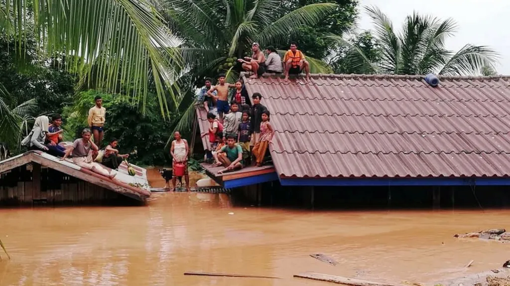 Lidé čekají na záchranu na střechách domů