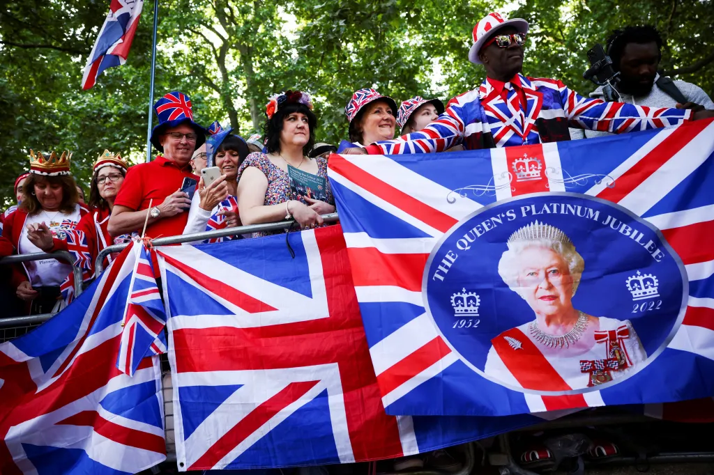 Lidé s transparenty oslavujícími sedmdesát let královny na trůně