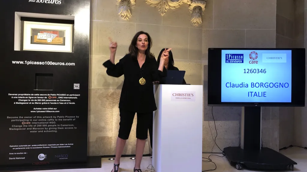 Moderátorka Peri Cochinová gestikuluje, zatímco jméno vítězkyně se objevilo na obrazovce v Paříži
