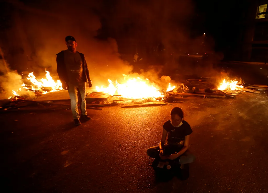 Demonstrantka sedí v tureckém sedu poblíž ohňů na ulici v Bejrútu. Ty byly zapáleny na protest proti neustále stagnující ekonomice a proti strmému pádu libanonské libry