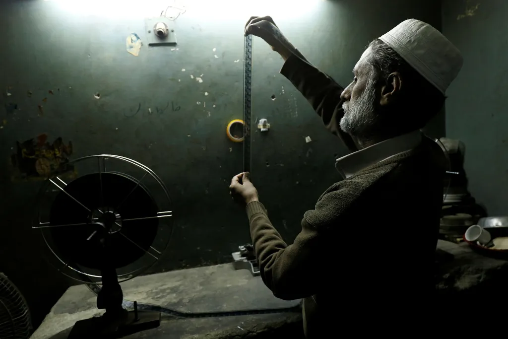 Promítač filmů kontroluje filmový pás v kině na předměstí pákistánského Péšávaru