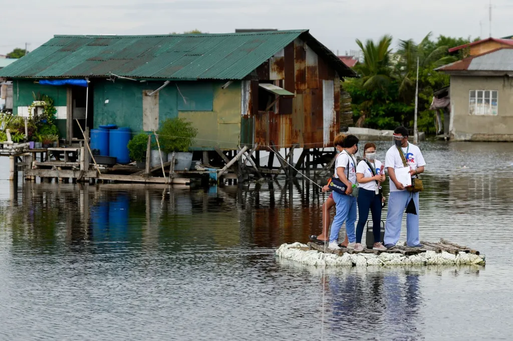 Filipínští zdravotníci přeplouvají na raftu mezi domy, aby nabídli očkování proti koronaviru lidem odkázaným na pobyt na lůžku