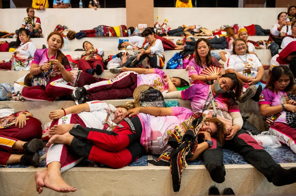 Při čekání na zahájení průvodu lidé odpočívají v ulicích hlavního města Filipín