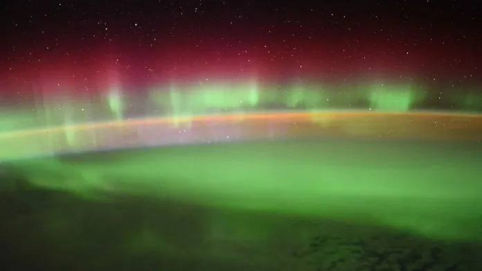 Polární záře nad zemským povrchem při pohledu z paluby Mezinárodní kosmické stanice ISS. Nejčastější červený a zelený odstín způsobuje emise kyslíku