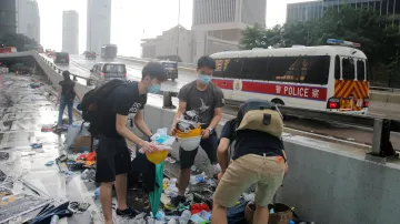Lidé si rozebírají masky, deštníky a další věci zanechané na místě střetů v Hongkongu