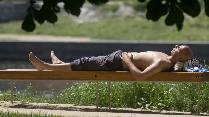 Muž se opaluje na Střeleckém ostrově v centru Prahy