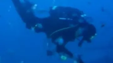 Potápěči-vinaři ukládají láhev sektu na dno moře