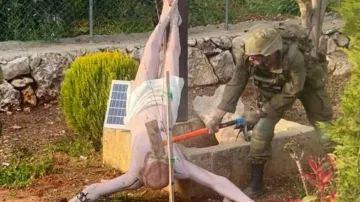 Izraelský voják ničí sochu Krista na kříži