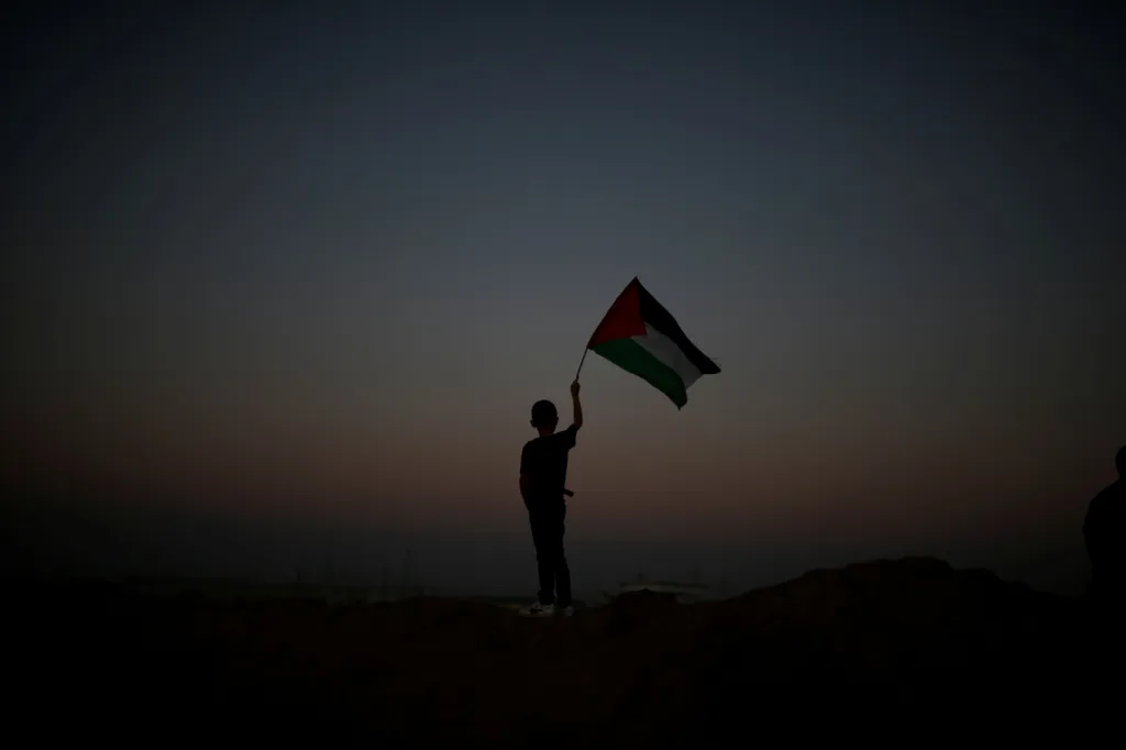Chlapec s palestinskou vlajkou při protestech na hranici Izraele a Palestiny. Palestinci při demonstracích na hranicích vyžadují právo vrátit se na svá území východně od města Gaza