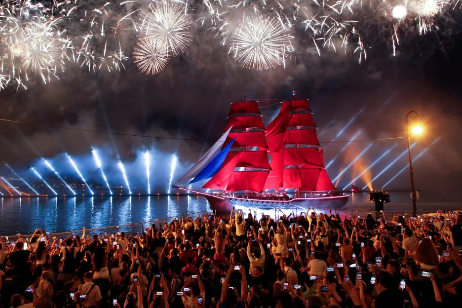 Diváci sledují explodující ohňostroj na obloze během každoroční největší akce v Petrohradě nazvané Scarlet Sails. Na snímku pluje plachetnice Rossija, na jejíž palubě se odehrává slavnost na počest absolventů námořní školy