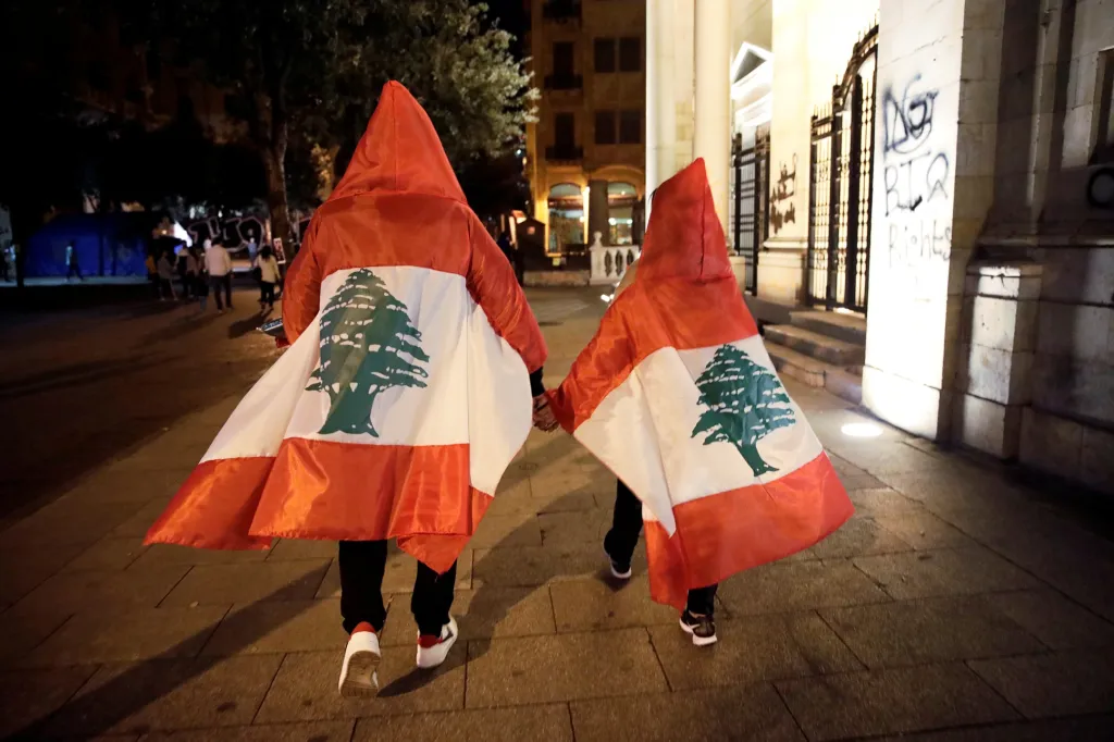 Pár s libanonskou vlajkou prochází ulicí Bejrútu během probíhajících protivládních protestů (2. listopadu 2019)
