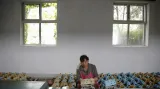 Dělnice v textilním zpracovatelském závodě Kim-Čong-Suk opravuje stroj během vládou organizované návštěvy pro zahraniční reportéry v Pchjongjangu.