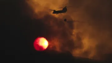 Hasičská helikoptéra nad kouřem z lesního požáru severně od Atén. Více než 350 hasičů a vojáků bojovalo v uplynulém týdnu po tři dny s rozsáhlými požáry v borovicových lesích nedaleko hlavního města.