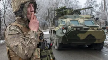 Ukrajinský voják kouří cigaretu vedle obrněného vozidla u Charkova