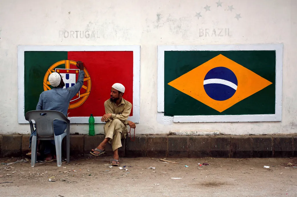 Fanoušci MS ve fotbale malují portugalskou a brazilskou vlajku na zeď v chudinské čtvrtí pákistánského Karáčí.