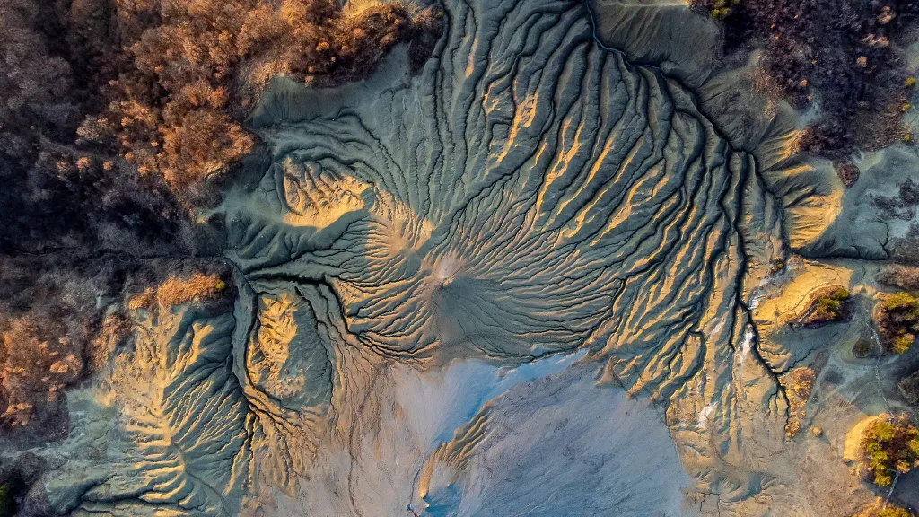 Alexandru George, Paclele Mari v Rumunsku: Mars na Zemi

Z výšky připomínají bahenní sopky v Paclele Mari mimozemský svět – popraskaný, vyřezávaný terén, kde Země dýchá skrz kužele bublajícího bahna. Tato letecká fotografie zachycuje surrealistickou krásu jedné z nejunikátnějších geologických formací Rumunska