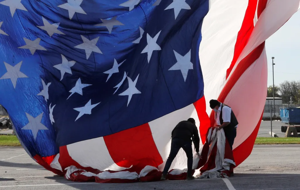 Techničtí pracovníci připravují americkou vlajku před místem volebního shromáždění demokratického kandidáta na prezidenta a bývalého víceprezidenta Joea Bidena v den voleb ve Wilmingtonu, ve státě Delaware