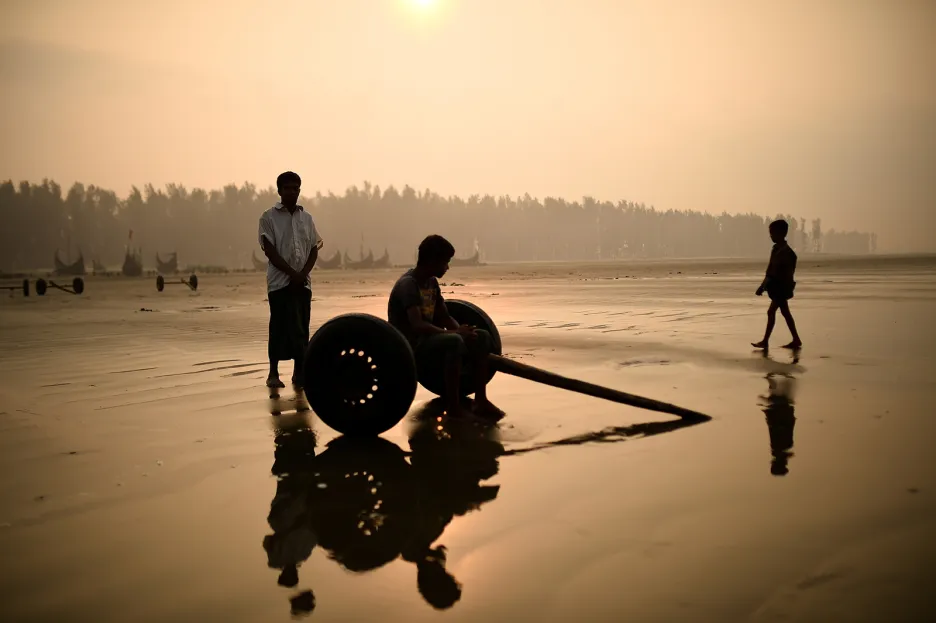 Rohingští uprchlíci posedávají na vozíku určeném k tažení rybářských sítí z vody na pláži Shamlapur v bangladéšském městě Cox's Bazar