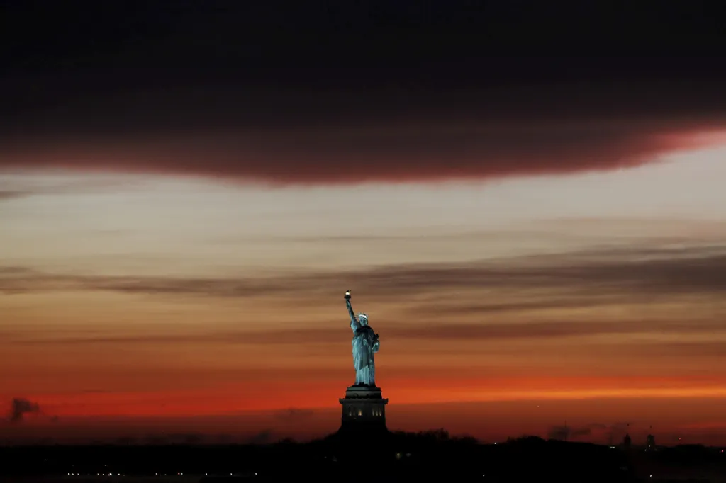 Západ slunce za sochou Svobody po dešťové bouři v New Yorku