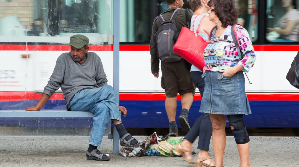 Bezdomovec na tramvajové zastávce v Olomouci