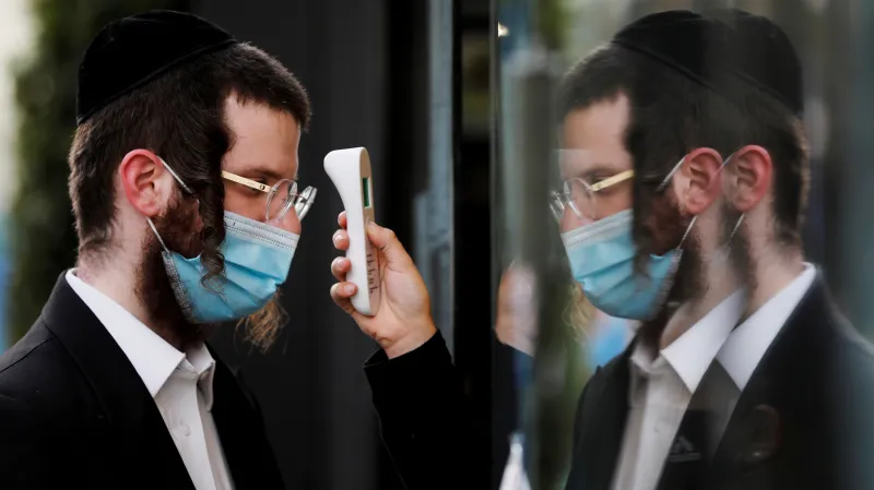 Návštěvník jednoho z obchodů v Ašdodu si nechává změřit teplotu