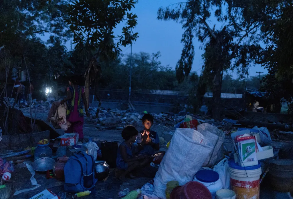 Děti Dharmendera Kumara sedí bez domova vedle svých věcí