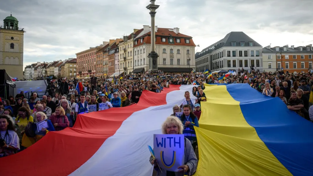 Poláci a Ukrajinci drží velké státní vlajky během shromáždění ke Dni nezávislosti Ukrajiny na Hradním náměstí ve Varšavě (24. srpna 2026)