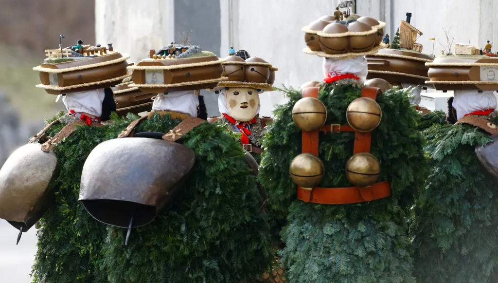 Muži oblečení v kostýmu postaviček "Chlaeuse"putují vesnicí Urnaesch ve Švýcarsku