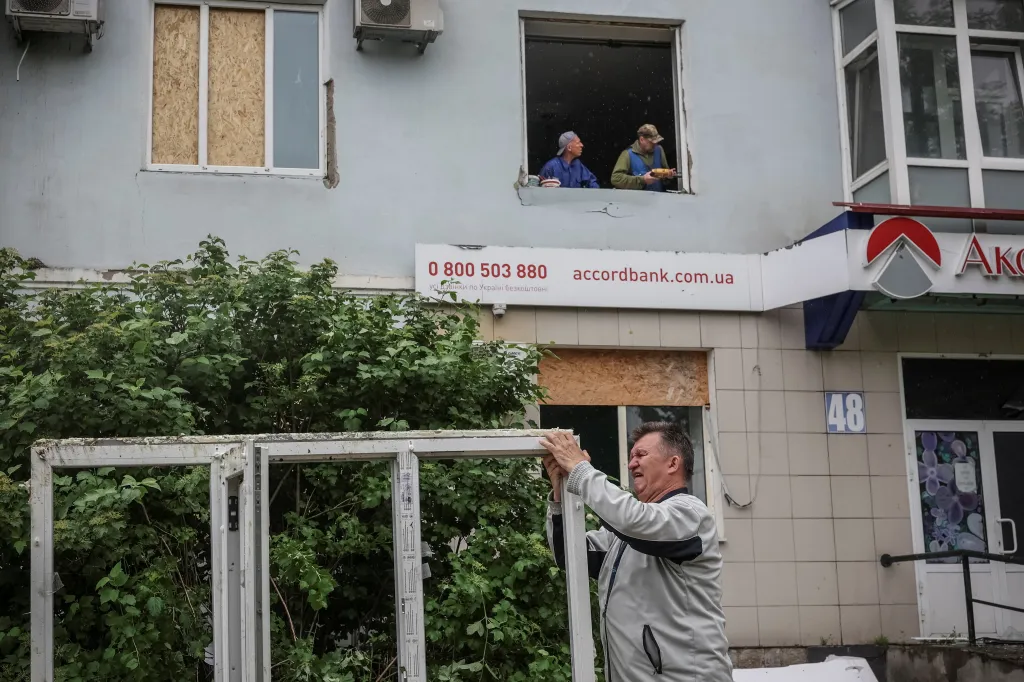 Obyvatelé obytných domů opravují okna poničená ruskými útoky z 27. 5. 2026