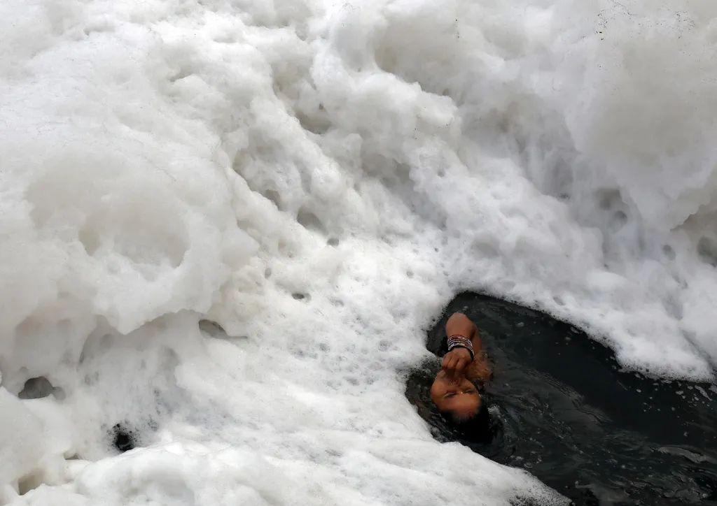 Hinduistka při koupeli ve znečištěné vodě řeky Yamuna před uctěním Slunečního boha během hinduistických svátků Chatth Puja v Novém Dillí