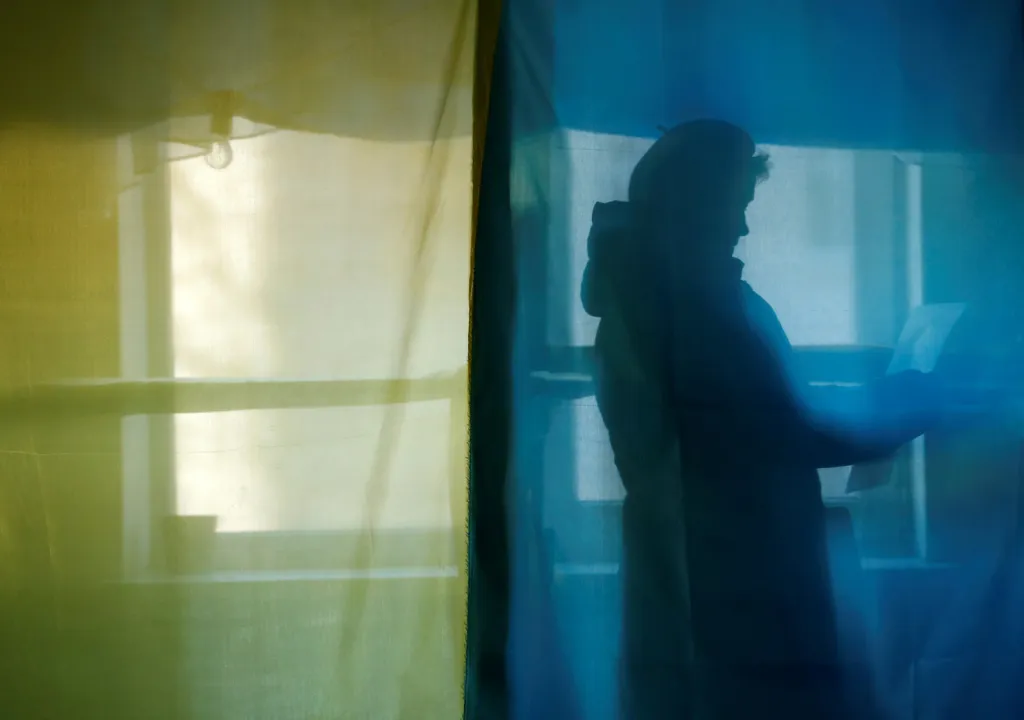 Žena uvnitř hlasovací kabinky ve volební místnosti během prezidentských voleb v obci Kosmach na Ukrajině