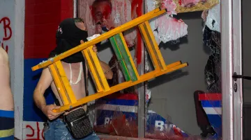 Jeden z demonstrantů rozbil okno během potyček mezi protivládními protestujícími a příznivci srbské vládní strany SNS v Novém Sadu (14. 8. 2025)