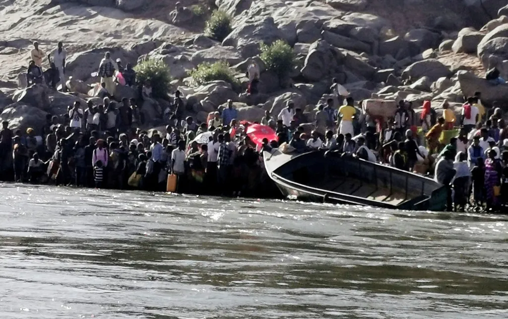 Fotografie ukazuje skupinu Etiopanů, kteří se připravují na překročení řeky Setit na hranici mezi Súdánem a Etiopií. Důvodem jsou nepokoje a probíhající boje v oblasti Tigraj