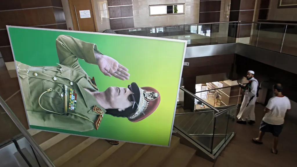 Povstalci odnášejí portrét Muammara Kaddáfího z hotelu Radisson