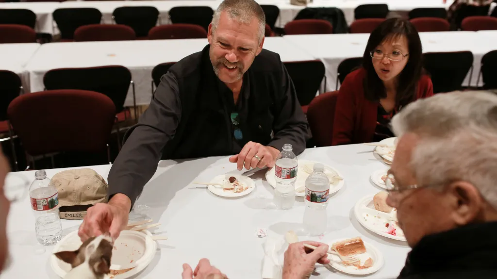 Jim Casler, kterému požár v Kalifornii zničil domov ve městě Paradise, krmí kouskem krocaní pečínky psa svého bratra při společném obědě organizovaném nadací World Central Kitchen s bratrem, švagrovou a otcem při oslavě Díkůvzdání v Chico State University ve městě Chico