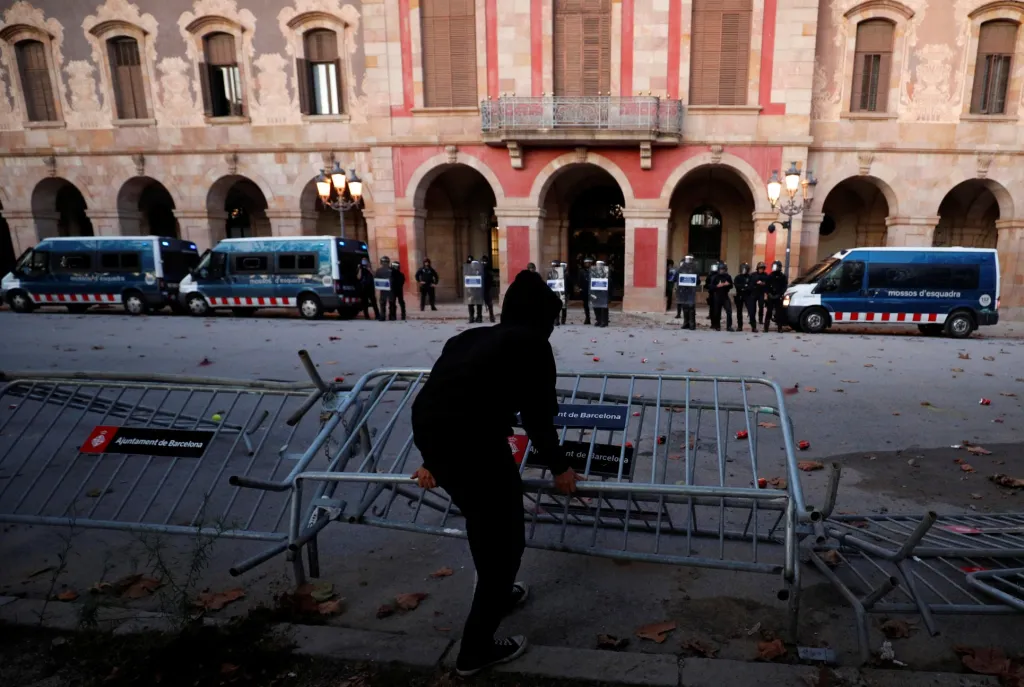 Jeden z demonstrantů odhazuje plotové zábrany před katalánským parlamentem