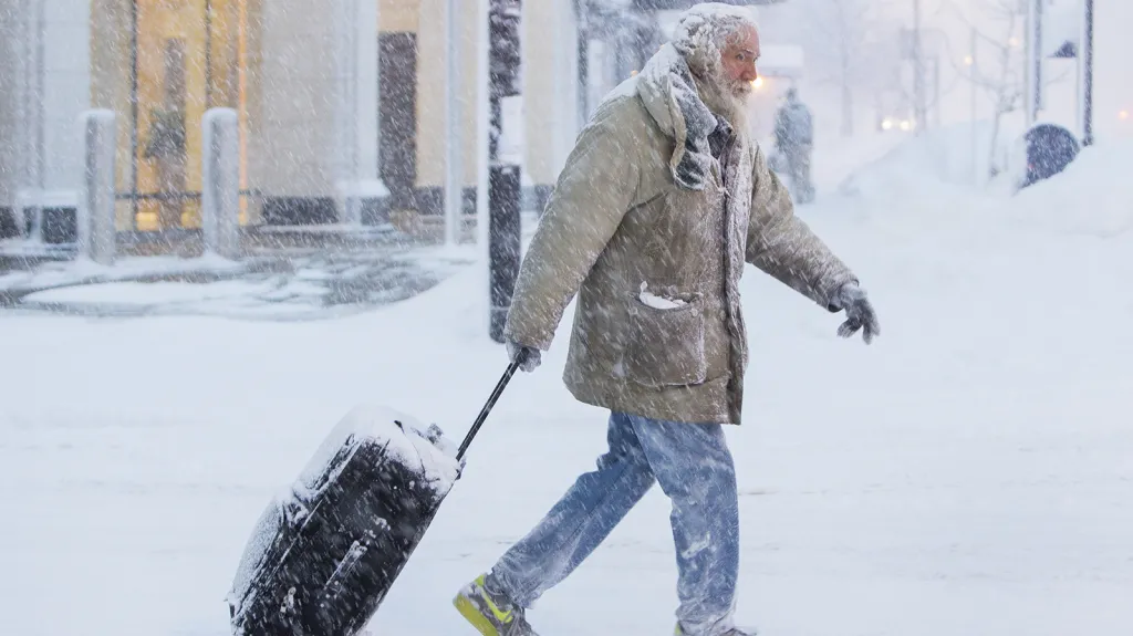 Muž ve sněhové bouři za hlubokého mrazu v ulicích města Buffalo
