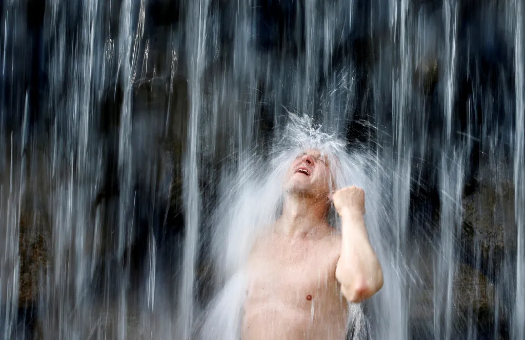 Muž při koupeli ve fontáně během horkých dní v běloruském městě Minsk.
